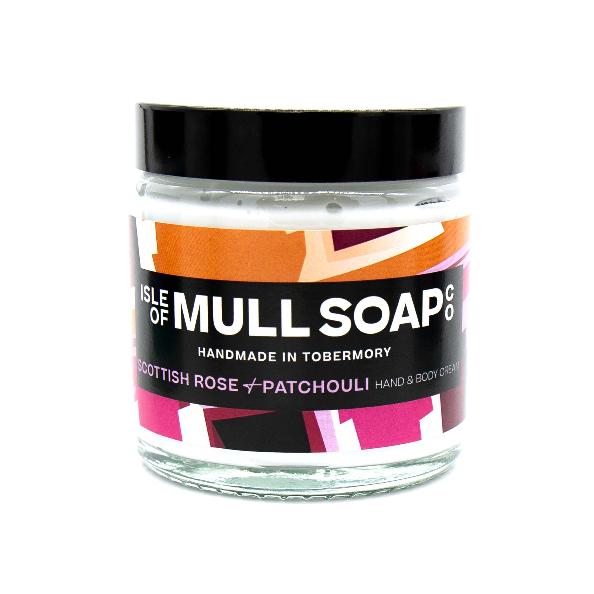 A glass jar with black lid. colourful pink label design, filled with Scottish rose and patchouli hand and body cream handmade in Tobermory by the Isle of Mull soap co. 